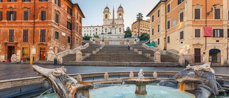 A historic square with a central staircase leading to a bell tower, surrounded by classical architecture.
