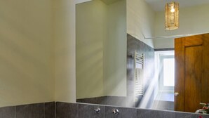 Un baño moderno con inodoro, lavabo y un espejo grande.