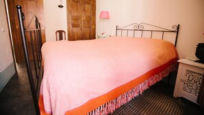Un dormitorio con una cama, un armario de madera, una mesita de noche y una lámpara.