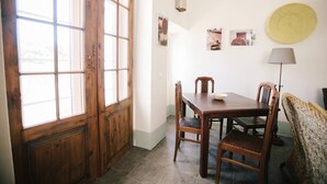 Un área de comedor con una mesa y sillas de madera, un banco tejido y una lámpara.