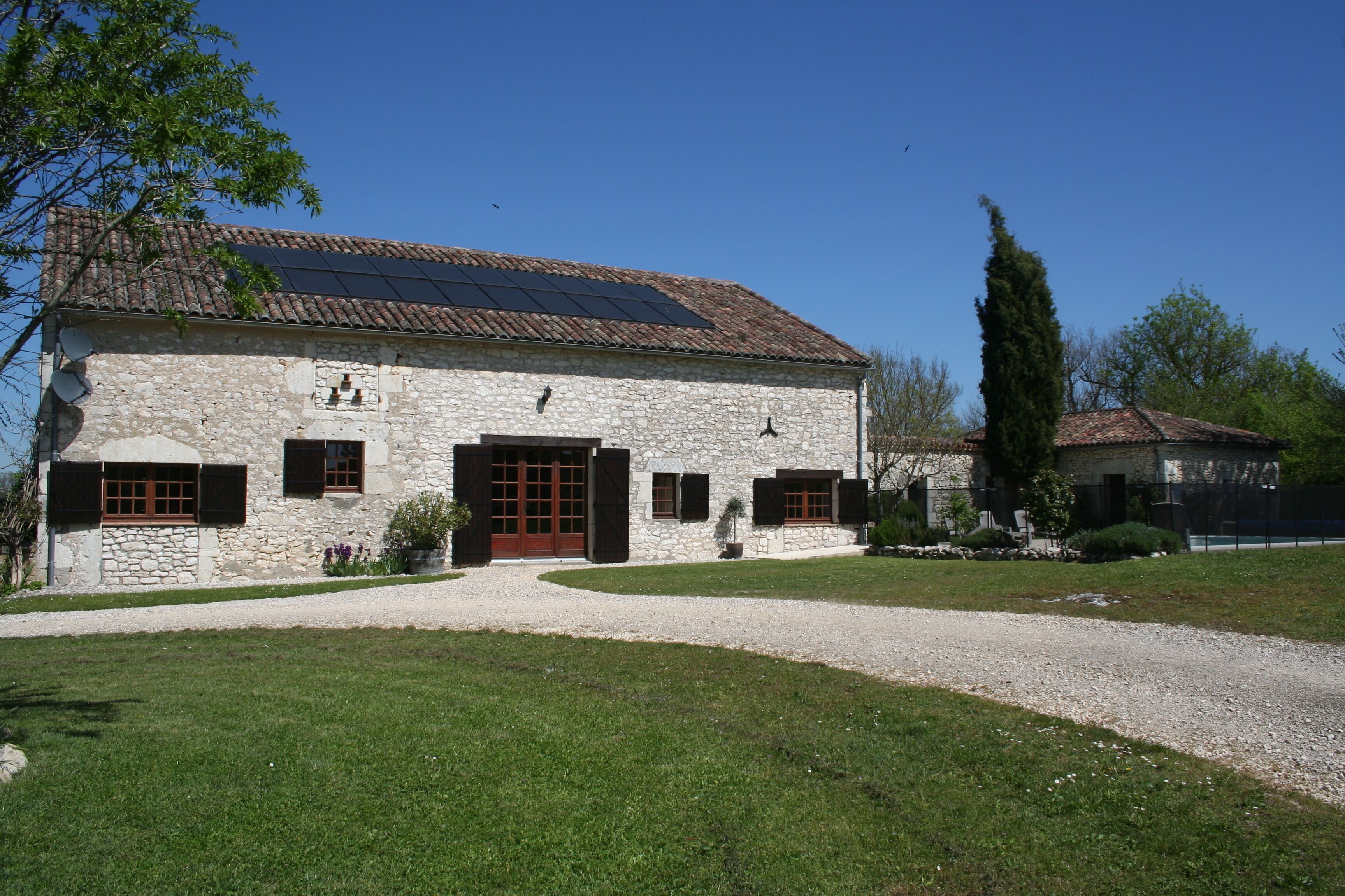 A stone building with a gravel driveway and a well-maintained lawn.