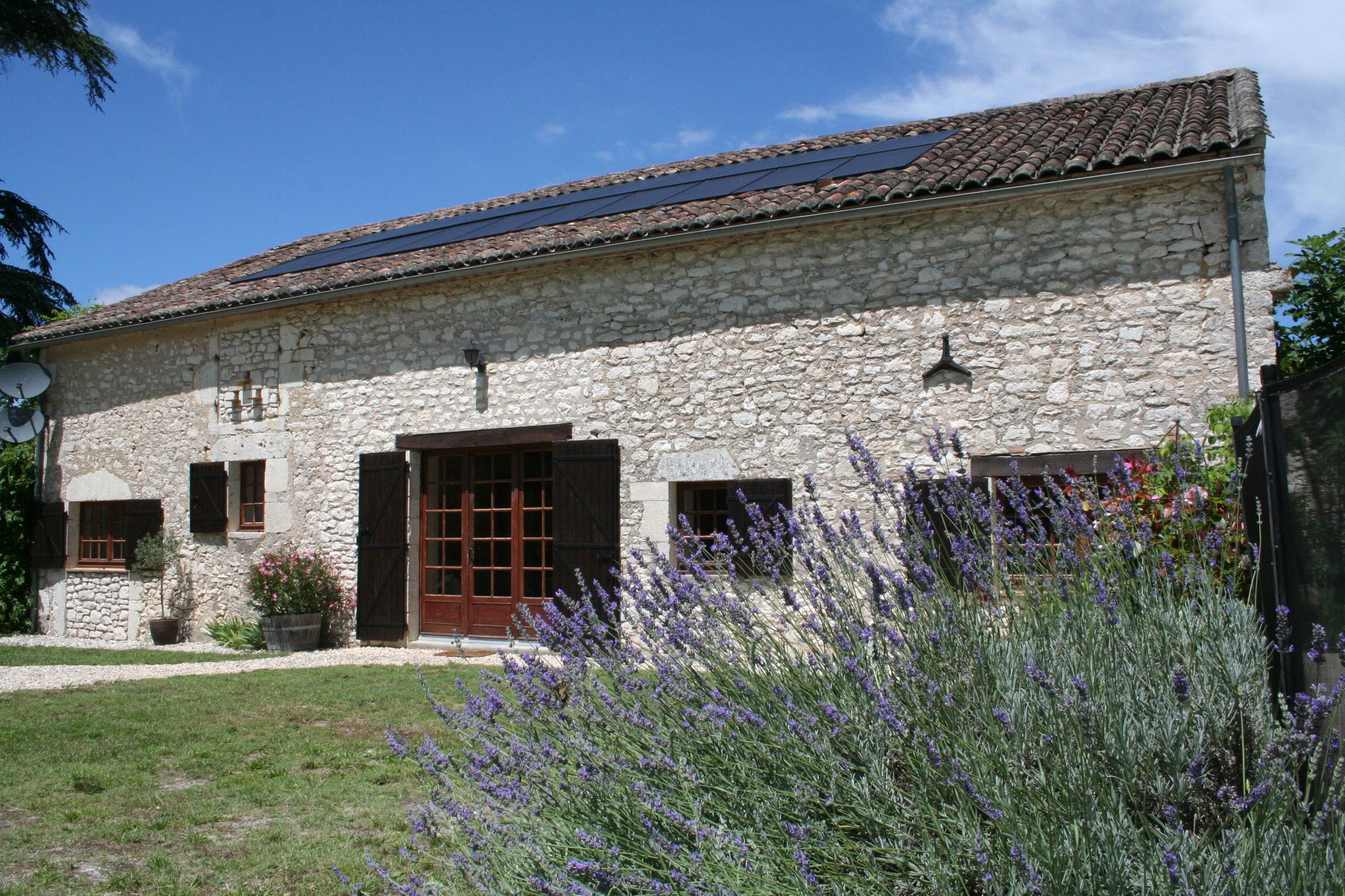 Un bâtiment en pierre avec un toit en tuiles, une porte en bois et une fenêtre avec des volets.