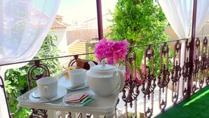 Un balcon avec une table mise pour le thé, comprenant des tasses, des soucoupes et une théière.