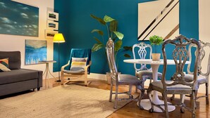 Un salon moderne avec un mur d’accent de couleur turquoise, un canapé gris, une table ronde avec des chaises et un lampadaire.