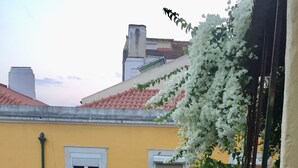 Un bâtiment jaune avec un toit recouvert de tuiles rouges, des fleurs blanches et une nappe blanche.