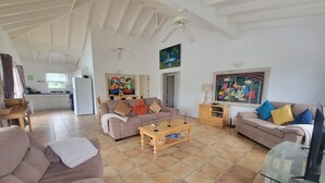 Ein geräumiges Wohnzimmer mit hoher Decke, Fliesenboden und zwei Sofas.