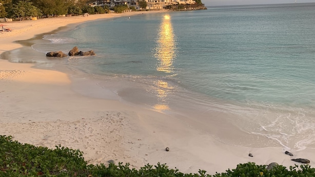 Ein Strand mit freiem Blick auf das Meer und einer Reihe von Gebäuden im Hintergrund.