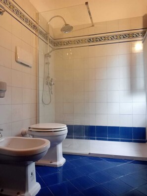 Une salle de bain avec une douche, deux toilettes et un lavabo.