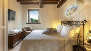 Un dormitorio con cama, una silla, un escritorio, una ventana y un cuadro en la pared.