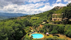 Una villa con piscina rodeada de abundante vegetación y montañas al fondo.
