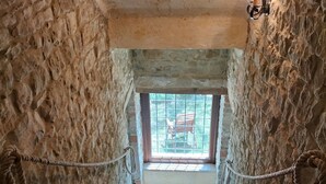 Una escalera de piedra que lleva a un ventanal con vistas a mobiliario exterior.