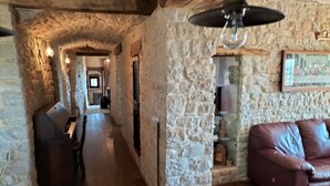 Un interior de paredes de piedra con un sofá de cuero, un lámpara colgante y una obra de arte enmarcada en la pared.