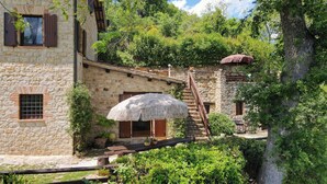 Un edificio de piedra con techo de paja, una escalera de madera y un pequeño jardín.