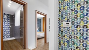 A modern bathroom with a shower, a toilet, and a sink. There is a wooden floor and a patterned wall. - Sea View Apartment on the bay of Naples last minutes discount 25 - 30 june (Castellammare di Stabia)