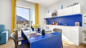 A modern kitchen with a blue countertop, white cabinets, and a view of a mountain. - Sea View Apartment on the bay of Naples last minutes discount 25 - 30 june (Castellammare di Stabia)