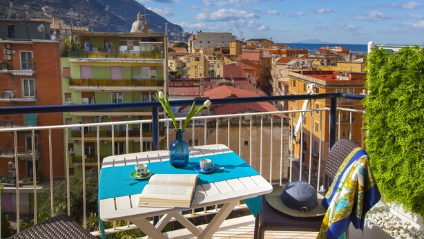 A balcony with a table, a book, a vase with flowers, and a hat. - Sea View Apartment on the bay of Naples last minutes discount 25 - 30 june (Castellammare di Stabia)