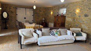 Una sala de estar acogedora con una pared de piedra, una mesa de comedor y un conjunto de sofás.