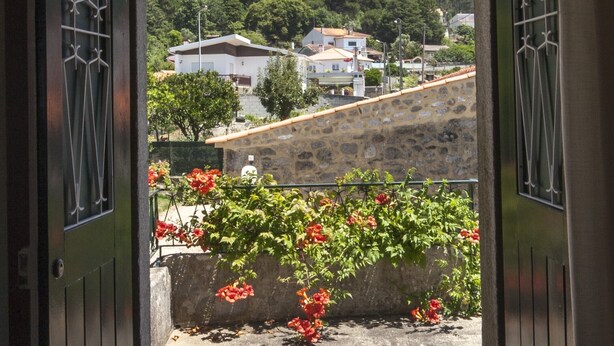 Una puerta que da a un balcón con vistas a una colina y casas.