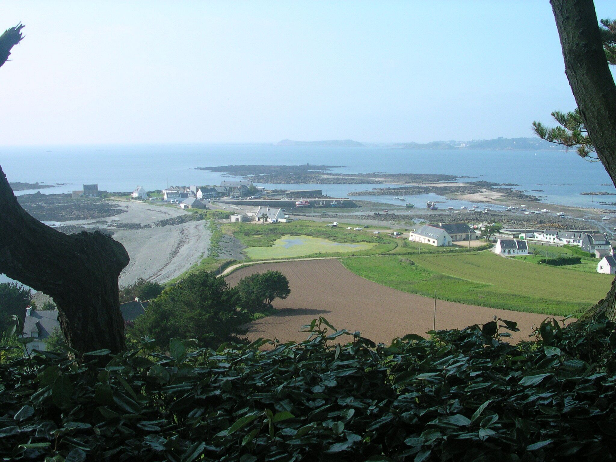 A coastal landscape with buildings, a golf course, and a view of the sea.
