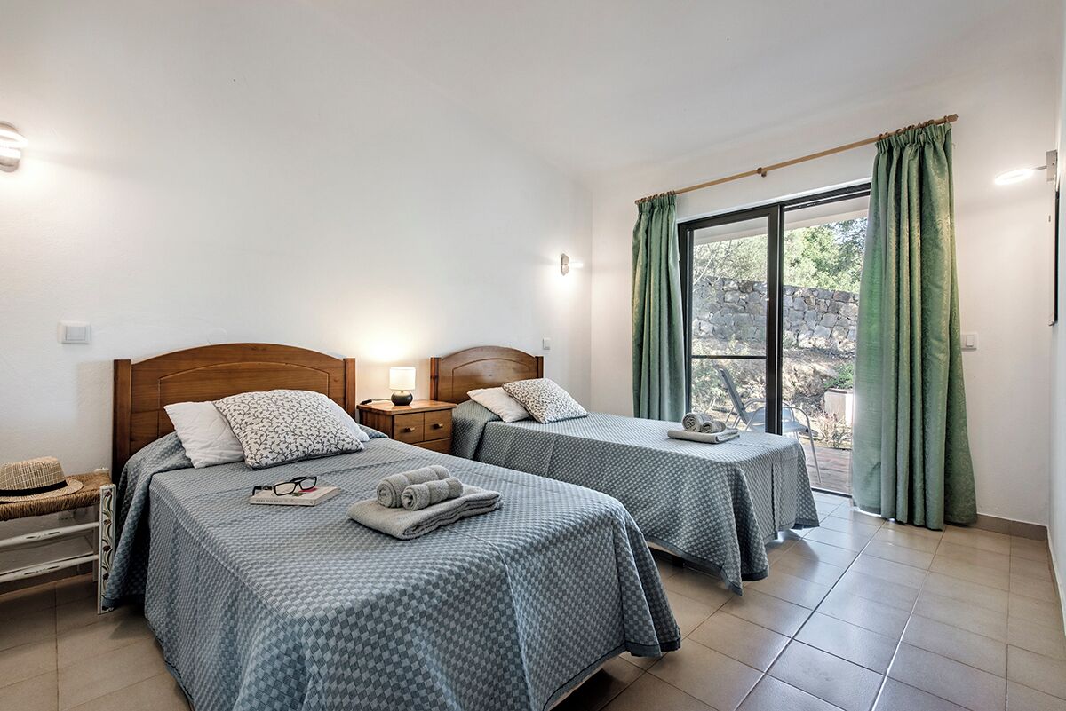 Une chambre d’hôtel avec deux lits, une petite table et une fenêtre avec des rideaux.