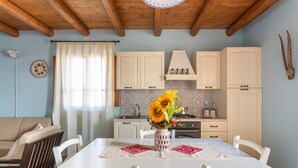 A cozy kitchen with a dining table, white cabinets, and a vase with sunflowers. - Ancient Mansion of the Arcolaio - F4856 (Nurachi)