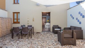 A patio with a stone floor, wicker furniture, and a view into a house. - Ancient Mansion of the Arcolaio - F4856 (Nurachi)