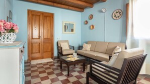 A living room with a checkered floor, wooden ceiling beams, a sofa, armchairs, and a coffee table. - Ancient Mansion of the Arcolaio - F4856 (Nurachi)