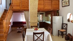 A cozy kitchen with wooden cabinets, a dining table with chairs, and a staircase leading to a loft bedroom.