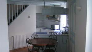 Una cucina compatta con zona pranzo, che include un tavolo di legno e sedie in metallo, un forno a microonde e una piccola finestra.