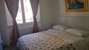 Une chambre à coucher avec un lit, des rideaux, un tableau et une fenêtre.