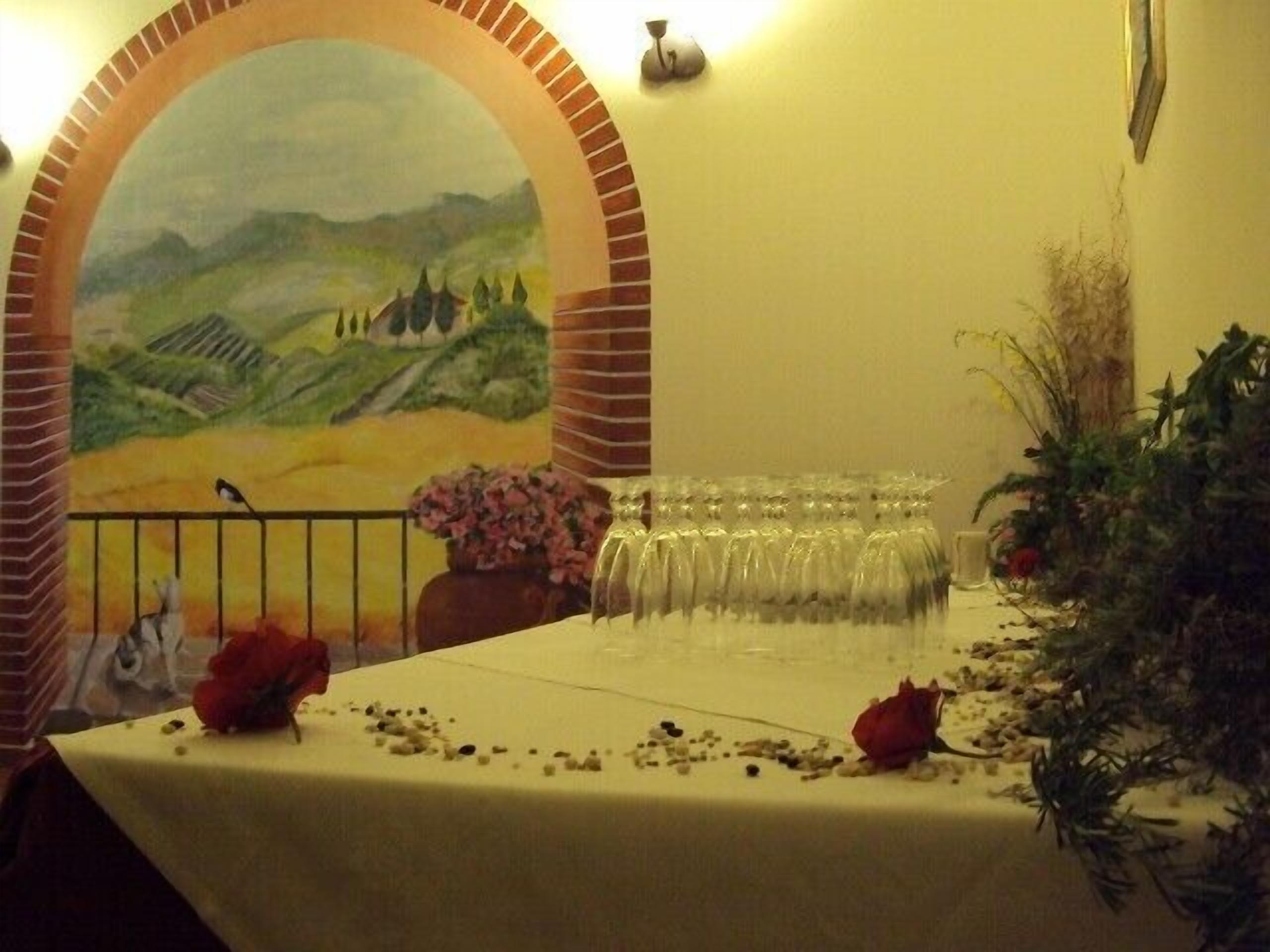 Ein Tisch ist mit einer weißen Tischdecke, einer Vase mit rosa Blumen und verstreuten Rosenblättern gedeckt.