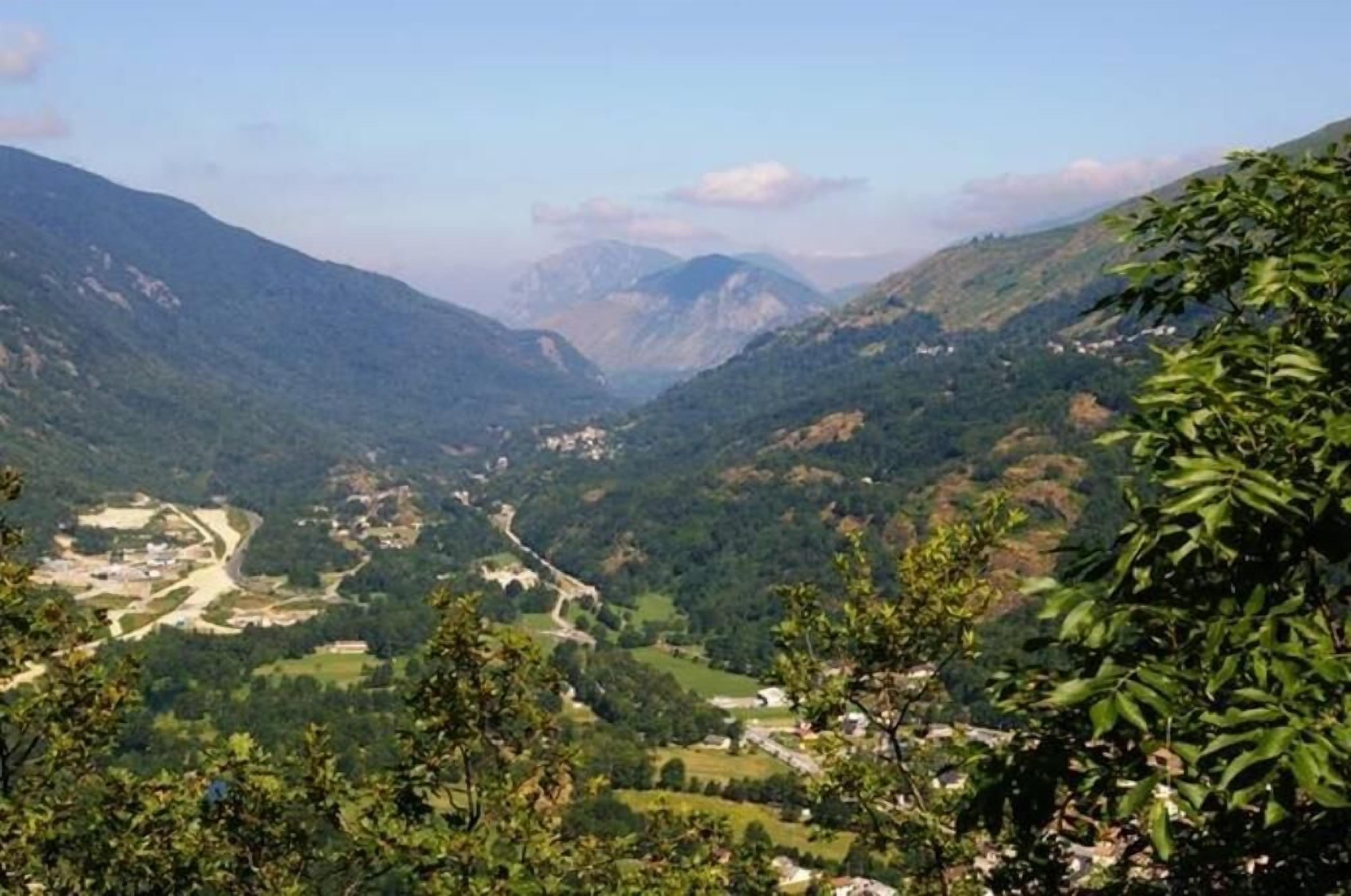 Un paysage montagneux, avec une route sinueuse et des bâtiments dispersés.