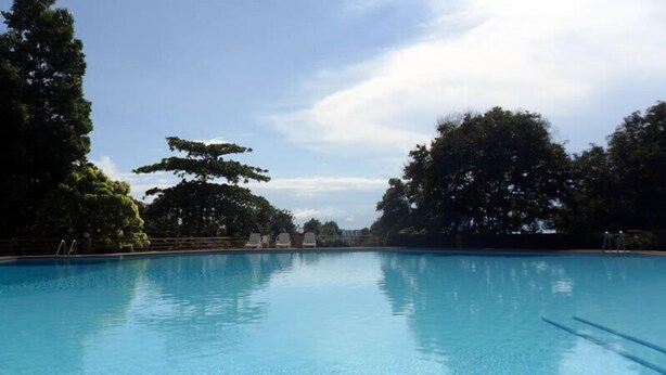 Une piscine d’eau bleue et limpide, entourée d’arbres, sous un ciel dégagé.