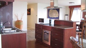 Une cuisine moderne dotée d’un îlot central, d’un évier en acier inoxydable et d’un four à micro-ondes.