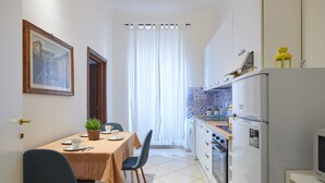 A compact kitchen with a dining area, featuring a table set for two, chairs, a refrigerator, and a microwave. - Characteristic Apartment in the City Center of Florence (Firenze)