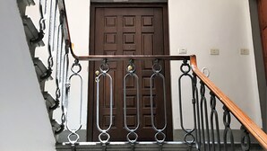 A staircase with a wooden handrail and metal balusters, leading to a door with a geometric light fixture above it. - Characteristic Apartment in the City Center of Florence (Firenze)