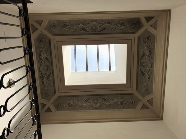 A room with a skylight, decorative ceiling, and a metal rack.