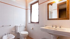 Un baño con inodoro, bidé, lavabo y espejo.