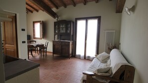 Una habitación con techo de madera, una mesa de comedor con sillas, un armario y un sofá.