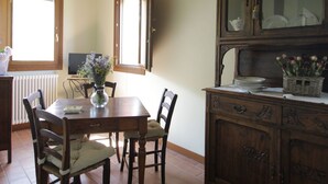 Un comedor con mesa y sillas de madera, un aparador con puertas de vidrio y una ventana con vistas.