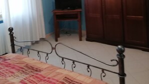 Une chambre à coucher avec un lit, un téléviseur posé sur un meuble, une armoire et un lustre.