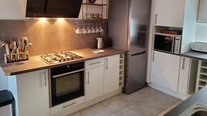 Cocina moderna con estufa a gas, horno, refrigerador de acero inoxidable, microondas y zona de café.
