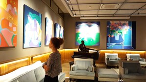 A lobby with a sofa, armchairs, a piano, and colorful artwork on the walls. - Except Nice. Duplex overlooking S'agaro Bay (S'agaro)