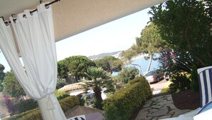 A balcony with a view of a coastal area, including a body of water and parked cars. - Except Nice. Duplex overlooking S'agaro Bay (S'agaro)