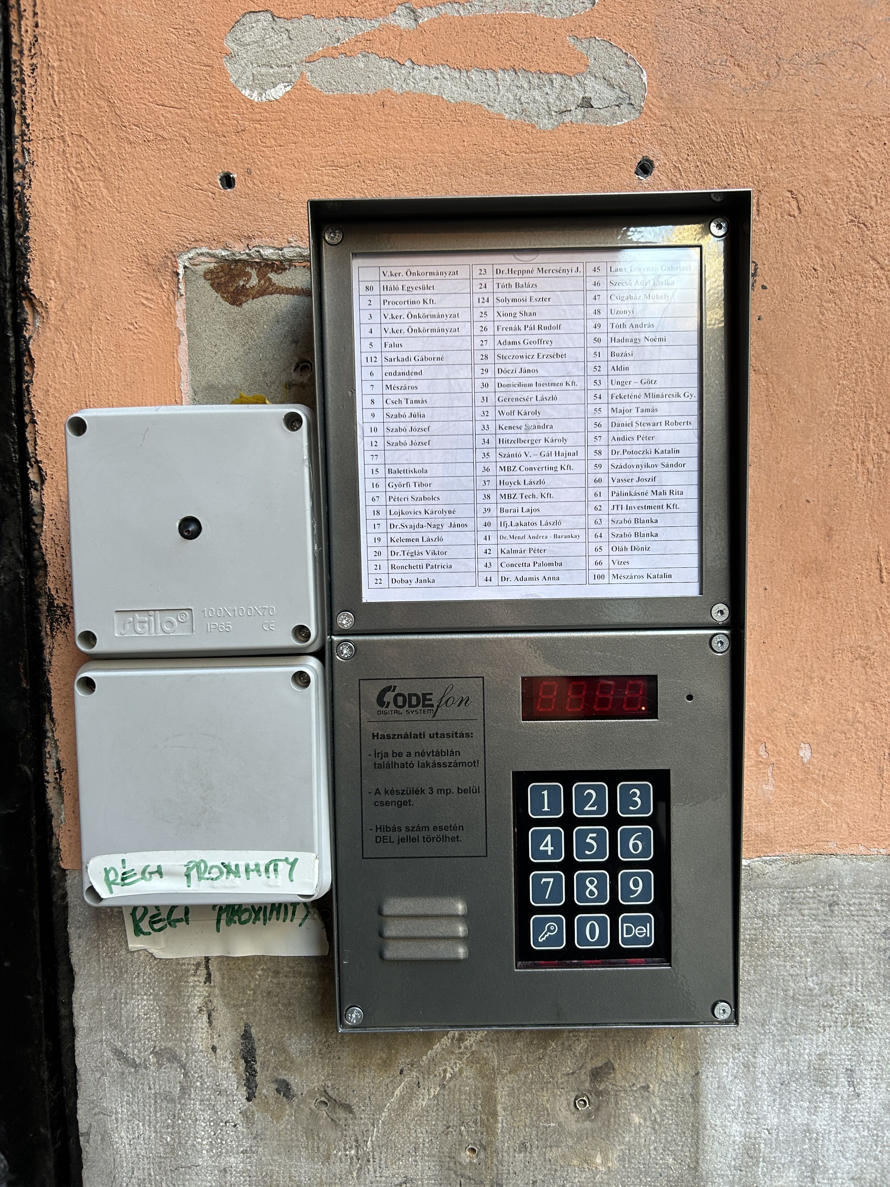 Ein Sicherheitstastenfeld mit digitaler Anzeige, einer Namensliste und einem kleinen Schild mit Anweisungen.