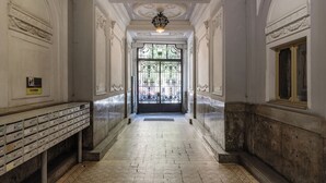 Ein Flur mit einer Bank, einer verzierten Decke und einer Tür mit einem Metallgitter.