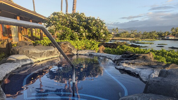 A hot spring area with a pool, rocks, and a wooden deck.