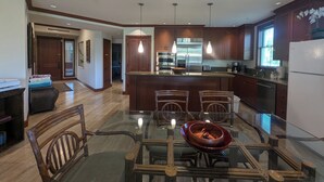 A modern kitchen with wooden cabinets, stainless steel appliances, and a glass dining table with chairs.
