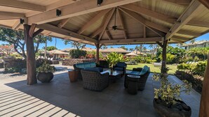 A covered outdoor seating area with wicker furniture and potted plants.