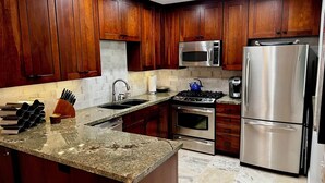 A modern kitchen with wooden cabinets, stainless steel appliances, granite countertops, and a built-in stove. - Beautiful & Romantic Downtown Private Pool & Spa.  Amazing Westerly facing views (Palm Springs)